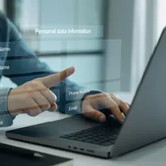 Osoba wpisuje dane osobowe, w tym adres i numer telefonu komórkowego, na ekranie laptopa.