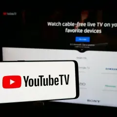 Smartfon z logo YouTube TV na tle ekranu telewizora z napisem "Watch cable-free live TV". Aktualizacja YouTube za darmo to świetna opcja.