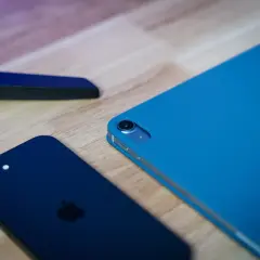 Ciemny iPhone i niebieski iPad na drewnianym blacie, gotowe do aktualizacji do iOS 13.