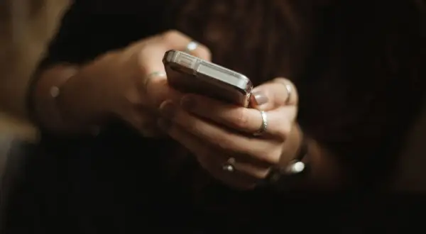 Dłonie z pierścionkami trzymają telefon, być może przeglądając oferty na OLX i myśląc o płatnościach PayPo.