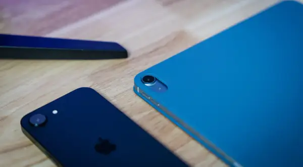 Ciemny iPhone i niebieski iPad na drewnianym blacie, gotowe do aktualizacji do iOS 13.