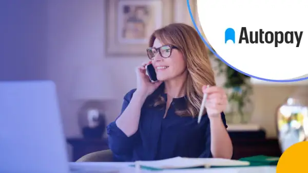 Kobieta w okularach rozmawia przez telefon, pracując przy laptopie. Rozwiązania autopay mobility ułatwiają jej codzienne życie.